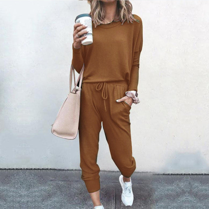 Frau in braunem Jumpsuit mit Kaffeebecher und Handtasche, lässiger Streetstyle, weiße Sneaker, Mode für Herbst, urbaner Look.