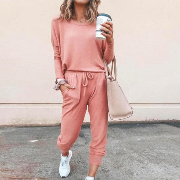 Frau in rosa Jogginganzug mit Kaffeebecher und beiger Tasche, lässiger Streetstyle, modische Freizeitkleidung, bequeme Damenmode.