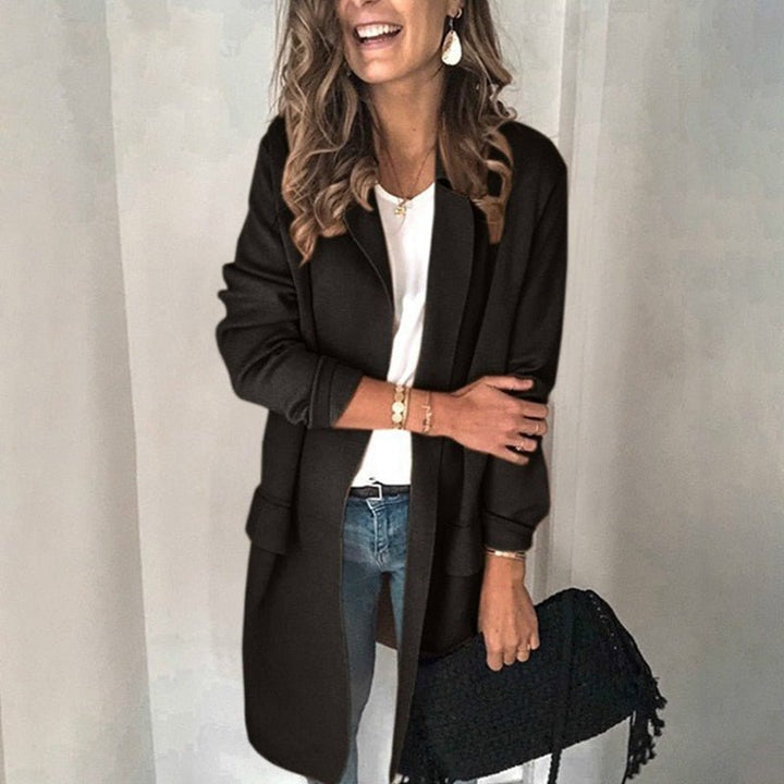 Frau in schwarzem Mantel, weißem Shirt und blauer Jeans, hält schwarze Tasche. Modetrend, Herbstmode, Damenbekleidung, stilvoller Look.