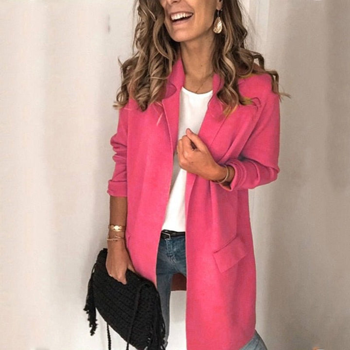 Frau in pinkem Blazer, weißem Shirt und blauer Jeans, hält schwarze Handtasche. Modetrend, stilvolle Damenbekleidung, lässiger Look.