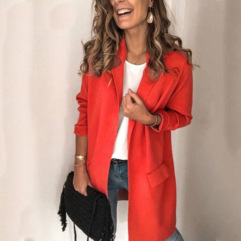 Frau in rotem Blazer, weißem Shirt und blauer Jeans, hält schwarze Handtasche. Modetrend, stilvolle Damenbekleidung, elegantes Outfit.
