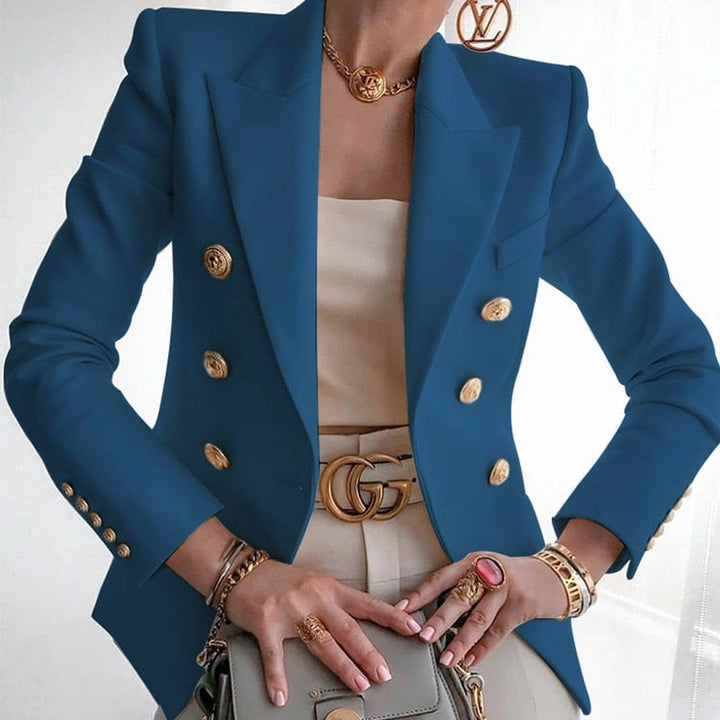 Frau in blauem Blazer mit goldenen Knöpfen, beige Top, Designer-Gürtel und Schmuck. Elegante Mode, luxuriöser Stil, Business-Outfit.