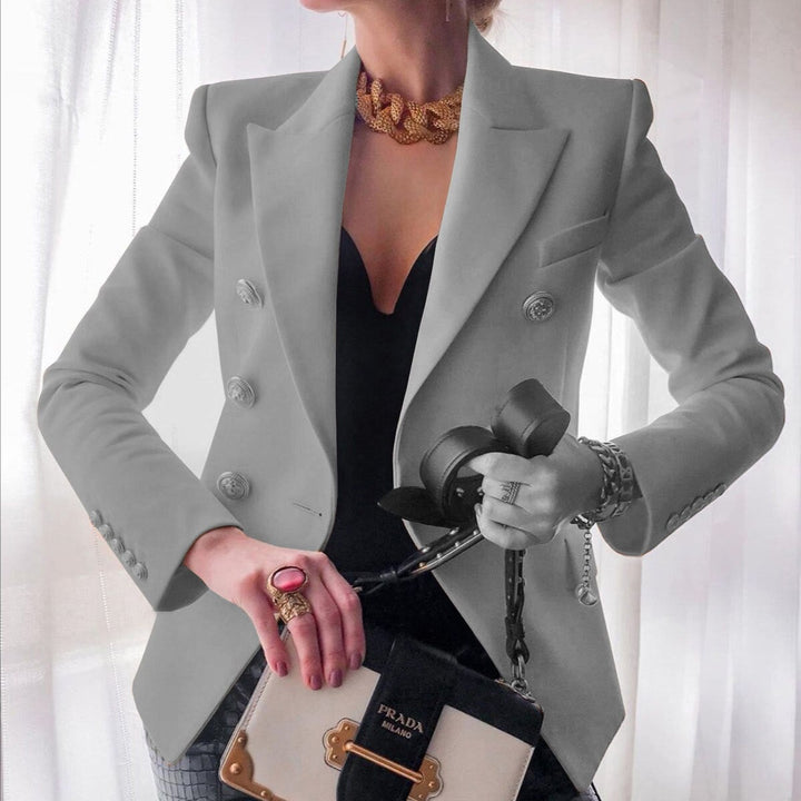 Elegante Frau in grauem Blazer mit goldener Halskette, schwarzem Kleid und Prada-Tasche. Stilvolle Mode, Luxusaccessoires, zeitloser Chic.
