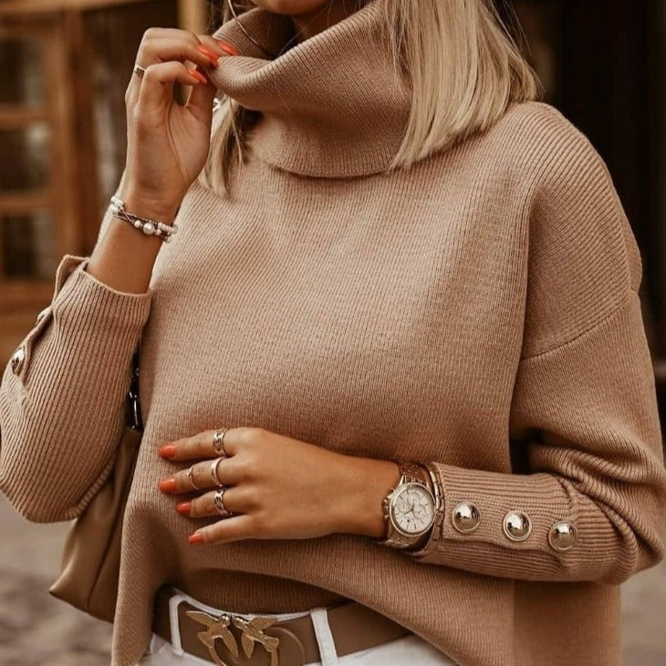Beige Rollkragenpullover mit Knopfleiste, getragen von Frau mit blonden Haaren. Accessoires: Armbanduhr, Armbänder, Ringe. Modischer Herbstlook.