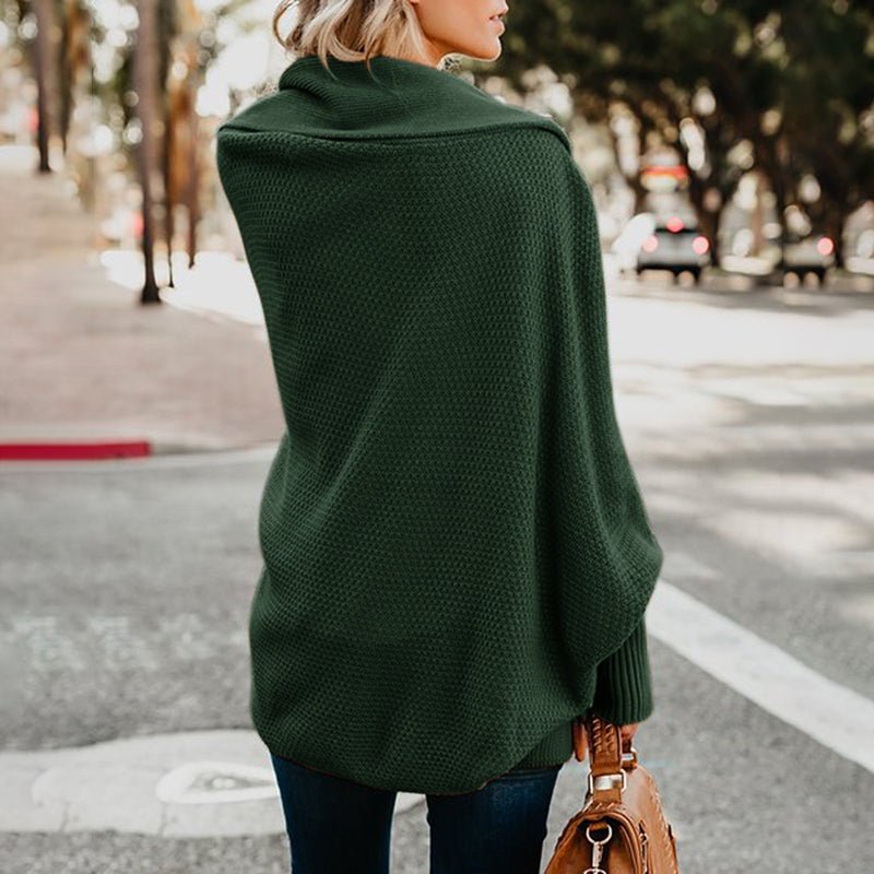 Frau in grünem Strickponcho auf Straße, trägt braune Handtasche. Herbstmode, lässiger Stil, Outdoor, Damenbekleidung, modischer Poncho.
