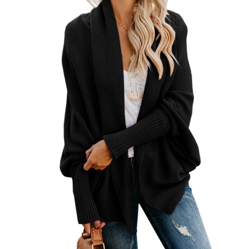 Frau in schwarzem Strick-Cardigan, weißem T-Shirt und blauen Jeans. Modetrend, lässiger Herbstlook, Damenmode, gemütlicher Stil.