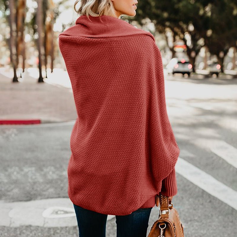 Frau in rotem Strickponcho auf Straße, Herbstmode, Rückansicht. Eleganter, warmer Poncho, ideal für kühle Tage. Trendige Damenbekleidung.
