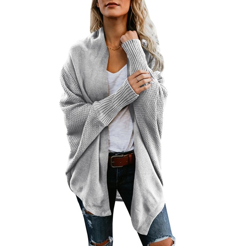 Frau in grauem Strickcardigan, weißem T-Shirt und zerrissenen Jeans. Modetrend, lässiger Herbstlook, Damenmode, gemütlicher Strickpullover.