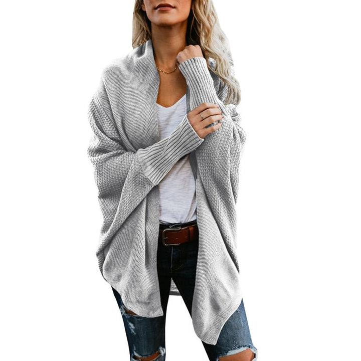 Frau in grauem Strickcardigan, weißem T-Shirt und zerrissenen Jeans. Modetrend, lässiger Herbstlook, Damenmode, gemütlicher Strickpullover.